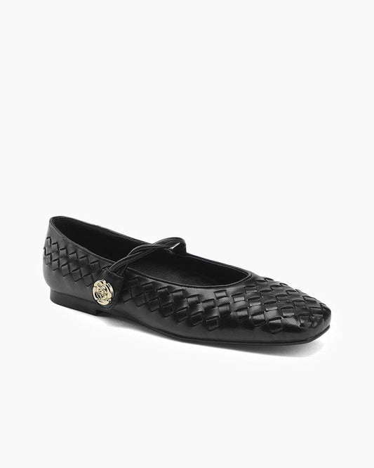 Black woven flat shoe with a gold emblem on a white background
